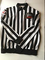 Front view of Bauer black and white striped referee jersey with OMHA patch and Hockey Canada arm patch