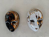 Front view of both miniature masks showing color schemes and decorative motifs