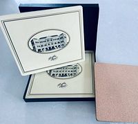 Box opened showing placemats, one flipped to display cork backing, visible printed Raffles Hotel design