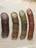 Four stacks of assorted coloured bangles laid out on cloth