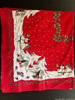 Red square tablecloth with snowman and holly border laid flat