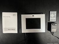 Front view of digital photo frame, remote, adapter, manual