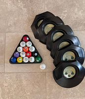All game components laid out including cups, racked billiard-style golf balls and cue ball