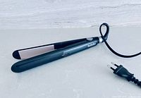 Hair straightener fully opened showing ceramic plates and attached Euro plug cord