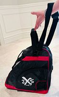 Side view of black and red 2XS triangular skate bag showing shoulder strap, handle and logo