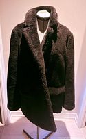 Front view of black teddy coat on stand
