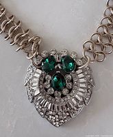 close-up of pendant showing green stones, clear baguette and round crystals