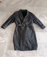 Front view of herringbone wool overcoat laid flat showing double-breasted closure and belt