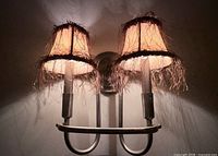 pair of cream fabric sconce shades illuminated on wall fixture