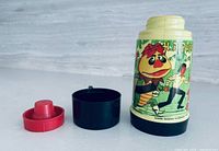 Full thermos with removed cup and stopper showing graphics and parts