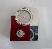 Front view of clock showing mahogany wood, chrome side, round analog face, Schulich medallion