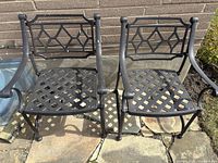 Two wrought iron patio chairs showing lattice seats and diamond back pattern