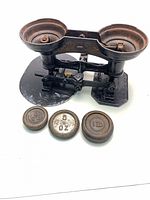 Full view of balance scale with two pans and both weights in front