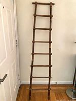 Full view of bamboo ladder leaning against wall, shows overall form and seven rungs