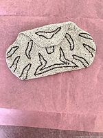 full view of ivory beaded clutch on pink tissue