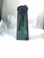 Front view showing blue-green glaze and maker’s mark at base