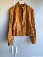Full view of tan leather jacket front on hanger