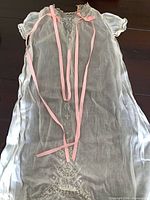 full view of sheer christening gown with ribbons