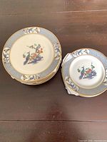 Stack of six large and three small plates showing design and gold rim