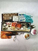 Full lot overview showing Coach notepad holder, pouch, jewelry tray, pill boxes, keychains