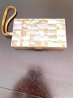 Front view showing mother-of-pearl tile exterior and wrist strap