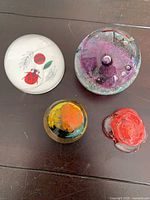 Group shot of the four glass paperweights showing size comparison and designs