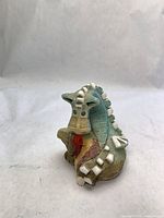 Front view of multicolor ceramic dragon figurine showing facial features and textured body