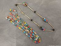 Two necklaces laid flat showing full designs and colours