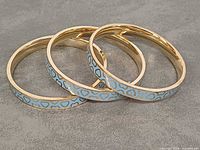 Three blue enamel gold-tone bangles angled side view