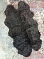 Full view of black faux sheepskin rug on patterned carpet