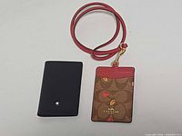 Front view of both card holders showing Montblanc logo and Coach design with lanyard