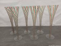 Six Murano champagne flutes front view displaying spiral ribbon pattern and clear bases