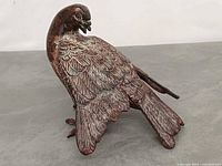 Left side view of metal pigeon figurine highlighting feather detail