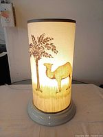Lamp illuminated showing camel and tree design, cord visible