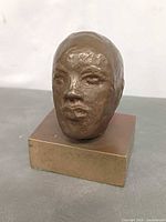 front view of bronze head on block base