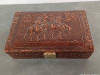 Angled view of closed box showing tooled leather exterior and brass latch