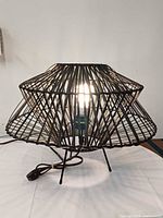 Lamp lit, showing overall form, wire shade, base and cord