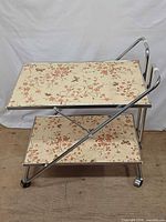 Front view showing two floral shelves and chrome frame on casters