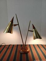 Front view showing brass frame, two cone shades, walnut base