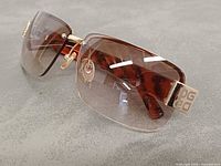 Front angled view showing rimless lenses, gold bridge, DG logo