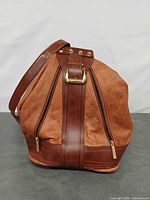 Front view of leather bucket backpack showing strap, zip pockets, hardware