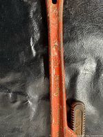 Close view of mid-handle showing red paint, cast markings, and rust