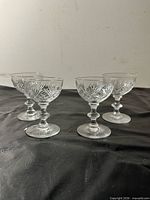 All four clear crystal champagne coupes grouped together on black surface