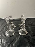 Group of four clear glass candlesticks on black surface