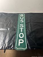 full view of vertical green BUS STOP sign on black surface