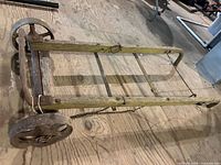 side view of vintage wooden hand truck showing frame, handle, wheels