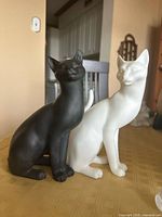 black and white cat figurines side by side on tabletop