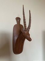 Full view of carved wooden gazelle head on plaque