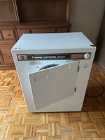 Front view of Hoover portable dryer with door ajar showing interior drum