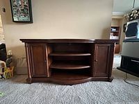 Front view of dark wood entertainment console showing side cabinets and open shelves